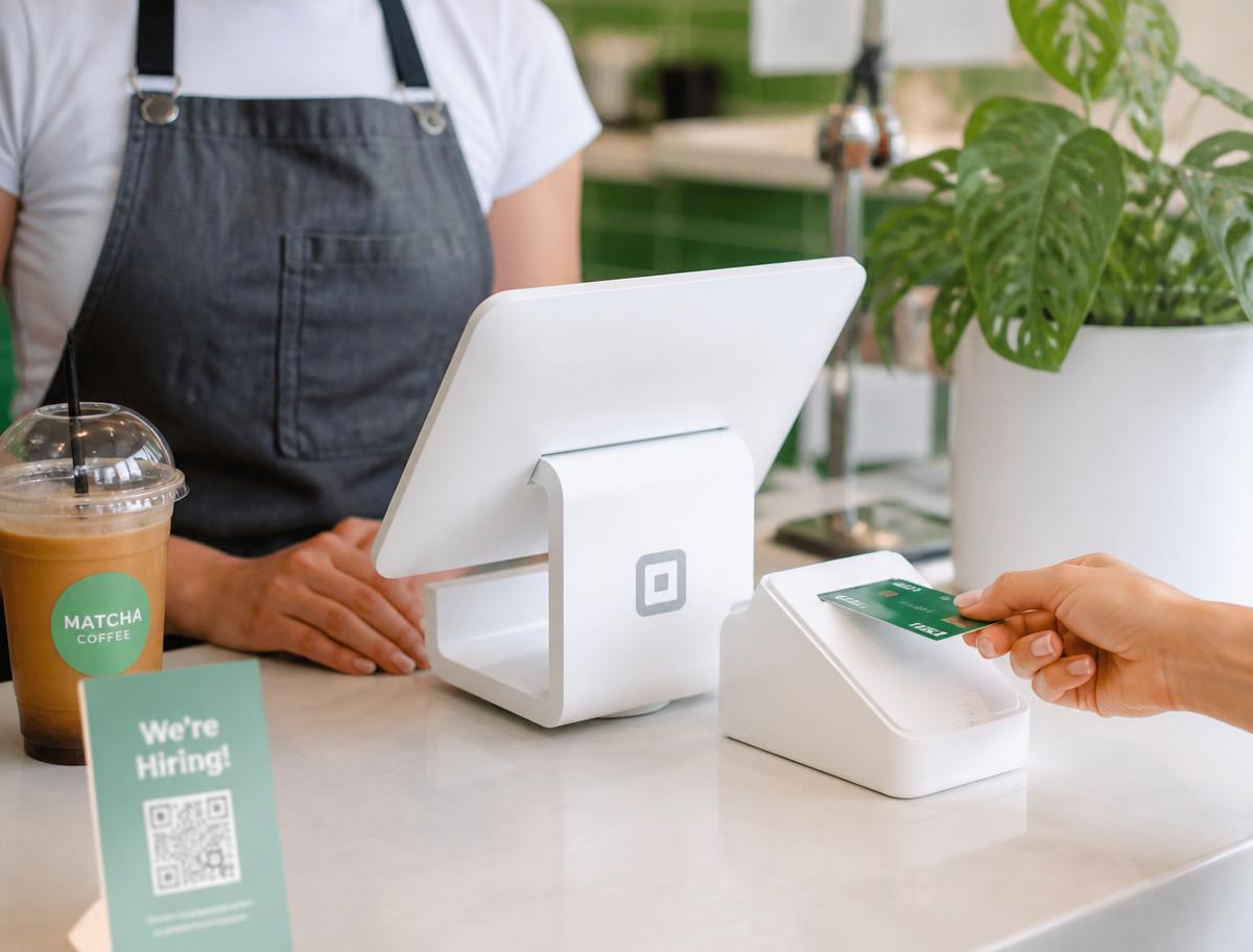 Customer swiping a credit card at a cafe checkout terminal